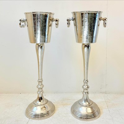 Lot 143 - PAIR OF POLISHED METAL CHAMPAGNE BUCKETS ON STANDS WITH HANDLES.